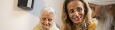 A carer and her parents sat on the sofa together.
